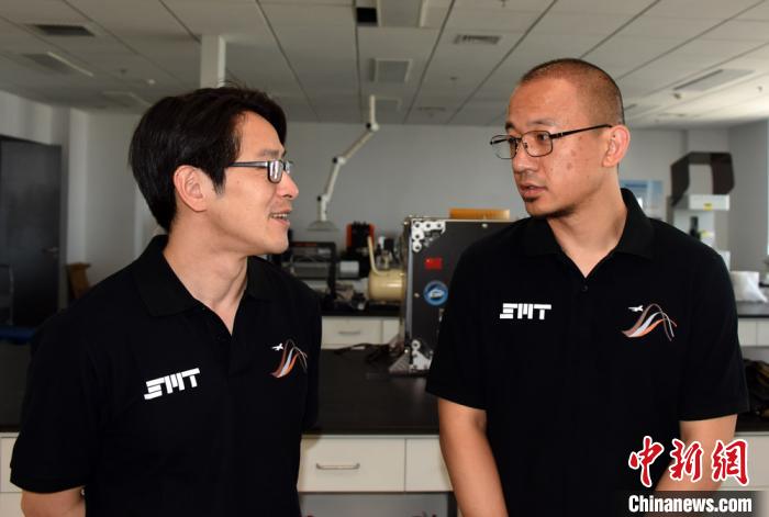 王功(右)与太空制造团队成员在实验室交流。　孙自法 摄