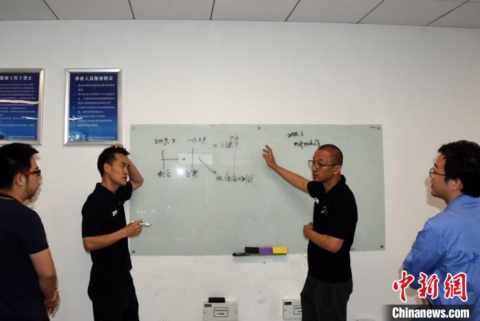 王功(右二)与太空制造团队成员在办公室复盘参与新飞船任务项目的过程。　孙自法 摄